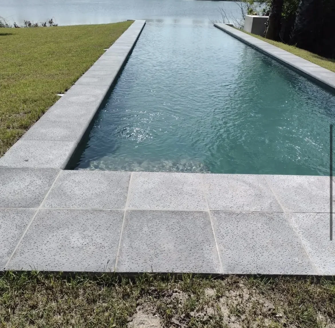 Piscina de líneas rectas con borde de losetas y césped
